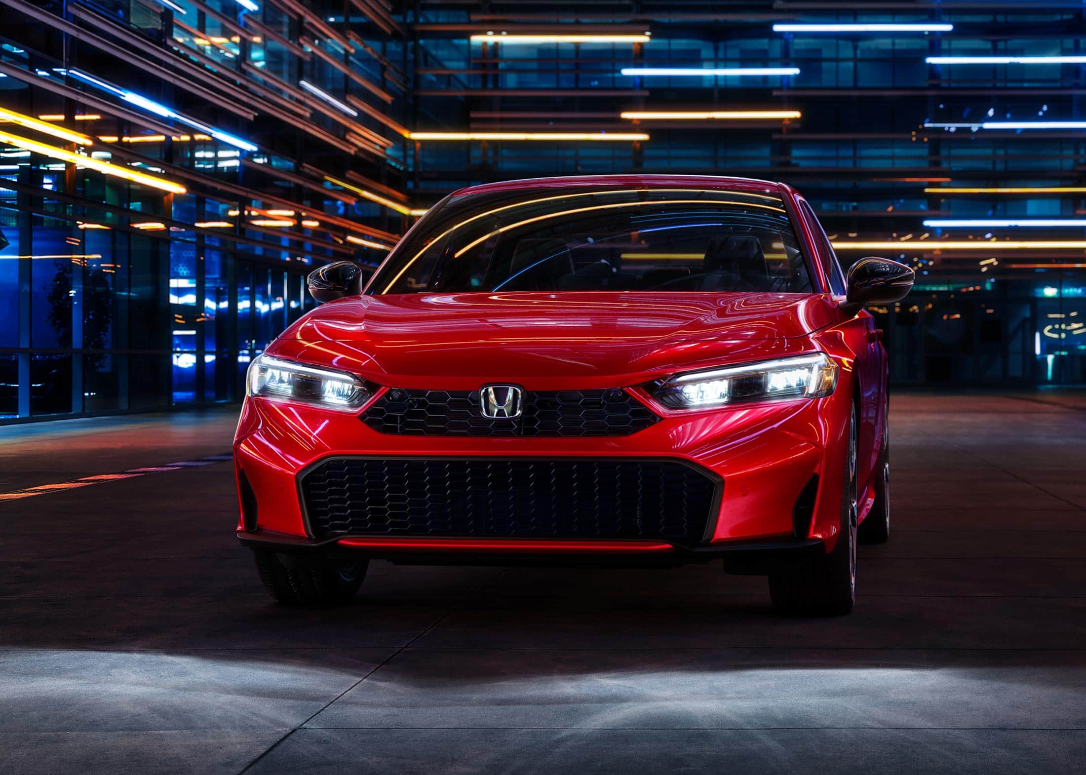 2026 Honda Civic Sedan Sport Touring Hybrid in Rallye Red front view with headlights on (Compact Sedan)